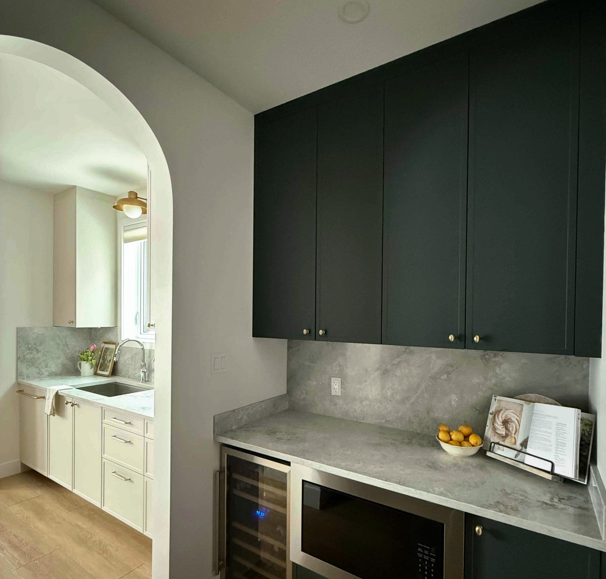 Deep forest green matte cabinet doors above a cream lower run and stone counter
